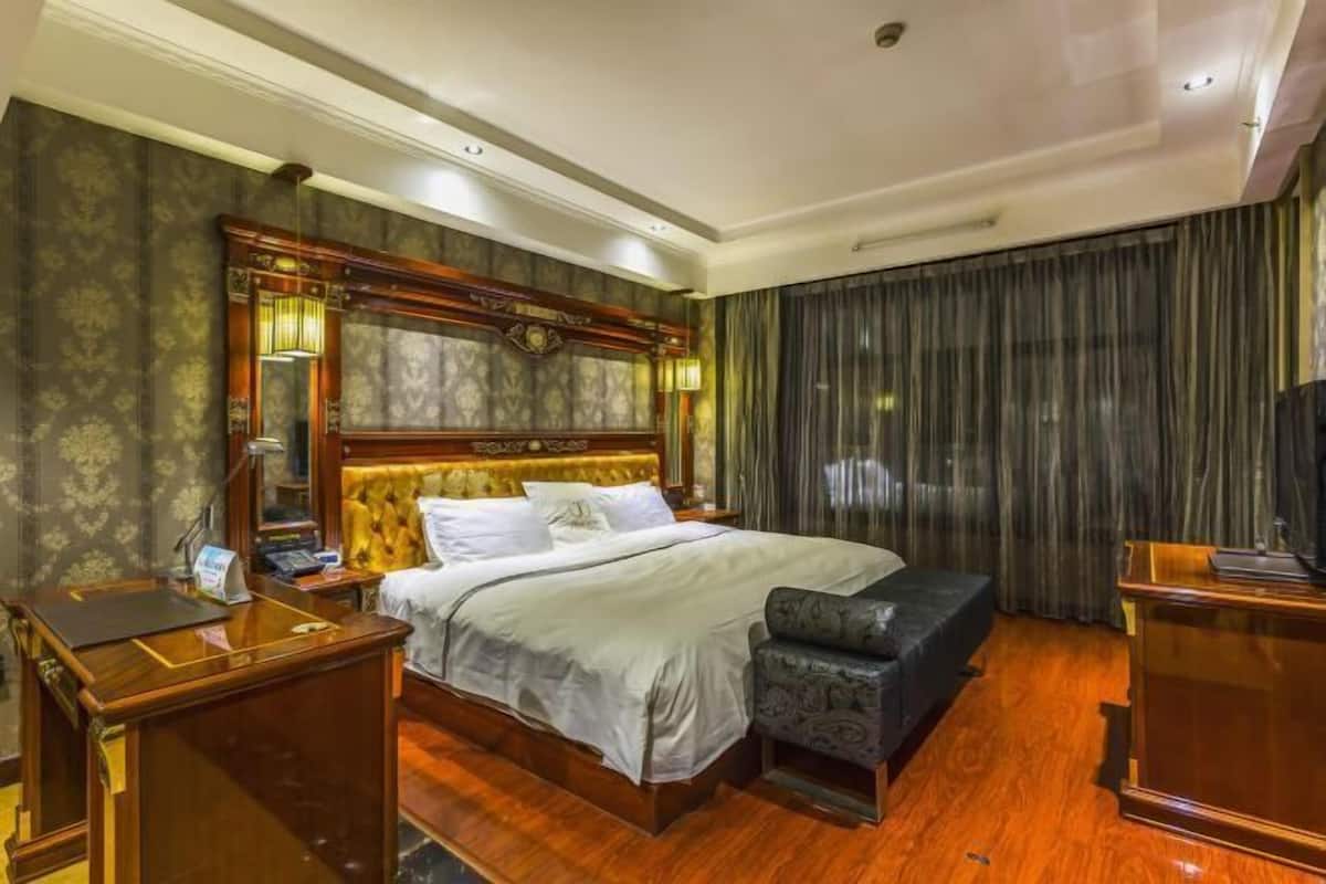 A hotel room with a large bed, a desk, a chair, and a television.