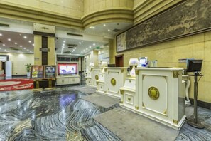 A lobby with marble flooring, a reception desk, a television, and a large painting on the wall. - Jiatai Hotel (Binzhou)