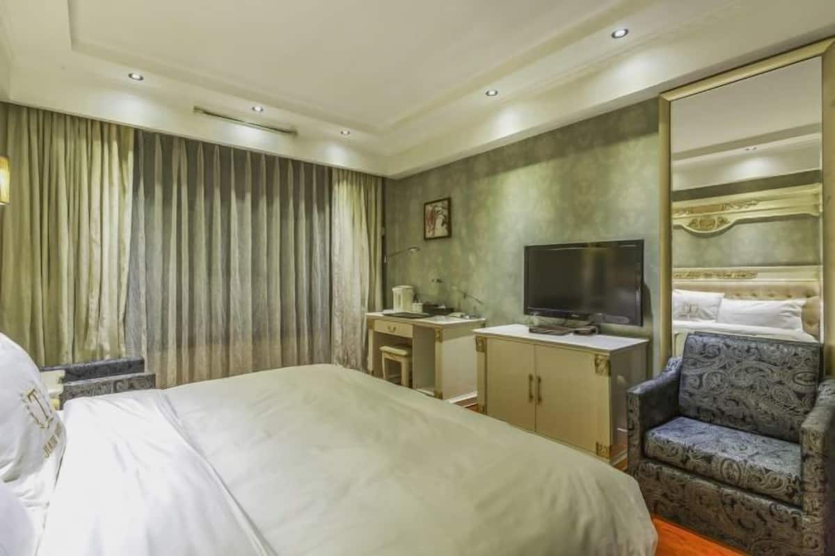 A hotel room with a bed, a television, a desk, and a chair.