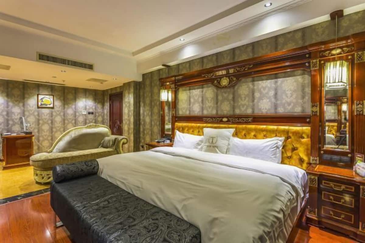 A hotel room with a large bed, a chair, a nightstand, and a mirror.