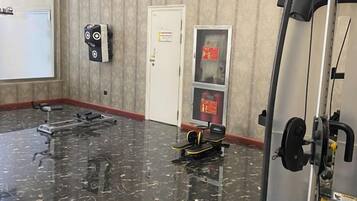 A gym with exercise equipment, a door with a sign, and a wall-mounted device.
