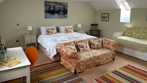 Ein Schlafzimmer mit Bett, Sofa, Schreibtisch und Stuhl. Es gibt ein Fenster und ein Oberlicht.