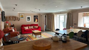Ein Wohnzimmer mit einem roten Sofa, einem Holztisch und einem Essbereich mit Tisch und Stühlen.