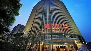 A tall, modern hotel building with a curved facade and illuminated signage. - Guidu Hotel Beijing (Beijing)