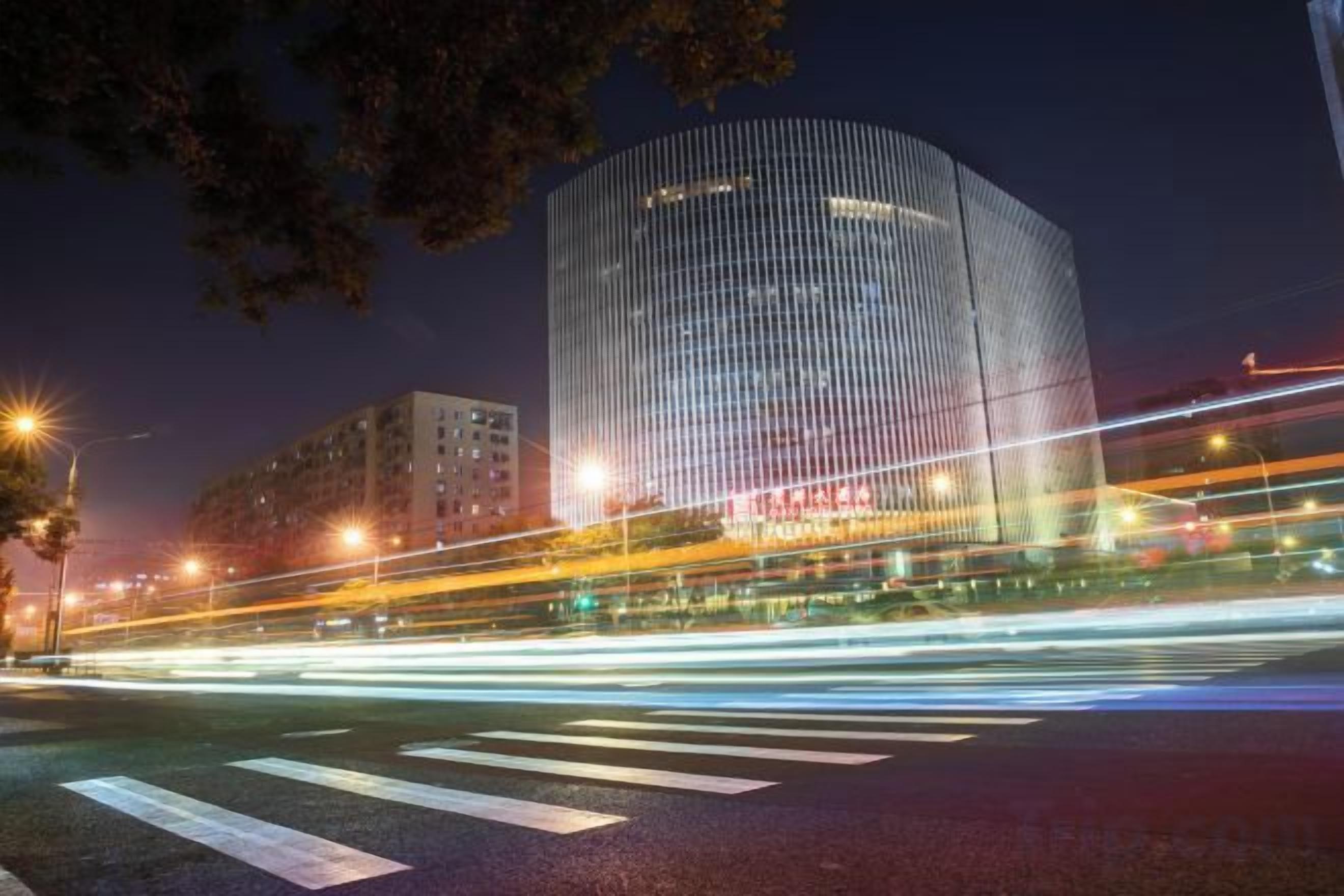 A modern building with a curved facade and a crosswalk in front.