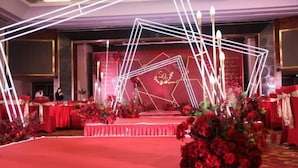 A stage with a red carpet, white geometric light structures, and red floral arrangements. - Guidu Hotel Beijing (Beijing)