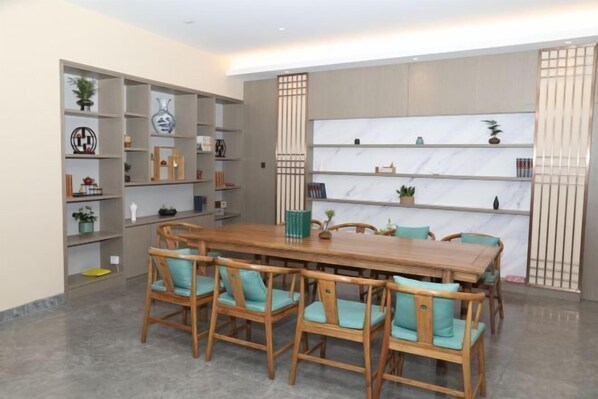 A dining area with a wooden table and chairs, surrounded by shelves with decorative items. - Guidu Hotel Beijing (Beijing)