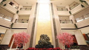 A multi-level atrium with a central column, decorative trees, and a fountain. - Guidu Hotel Beijing (Beijing)
