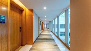 A long, narrow hallway with wooden walls and a patterned floor, leading to a bright area with large windows. - GreenTree Inn (Feicheng Xincheng Road) (Feicheng)