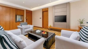 A modern living room with a sofa set, a coffee table, a flat-screen TV, and wooden paneling. - GreenTree Inn (Feicheng Xincheng Road) (Feicheng)