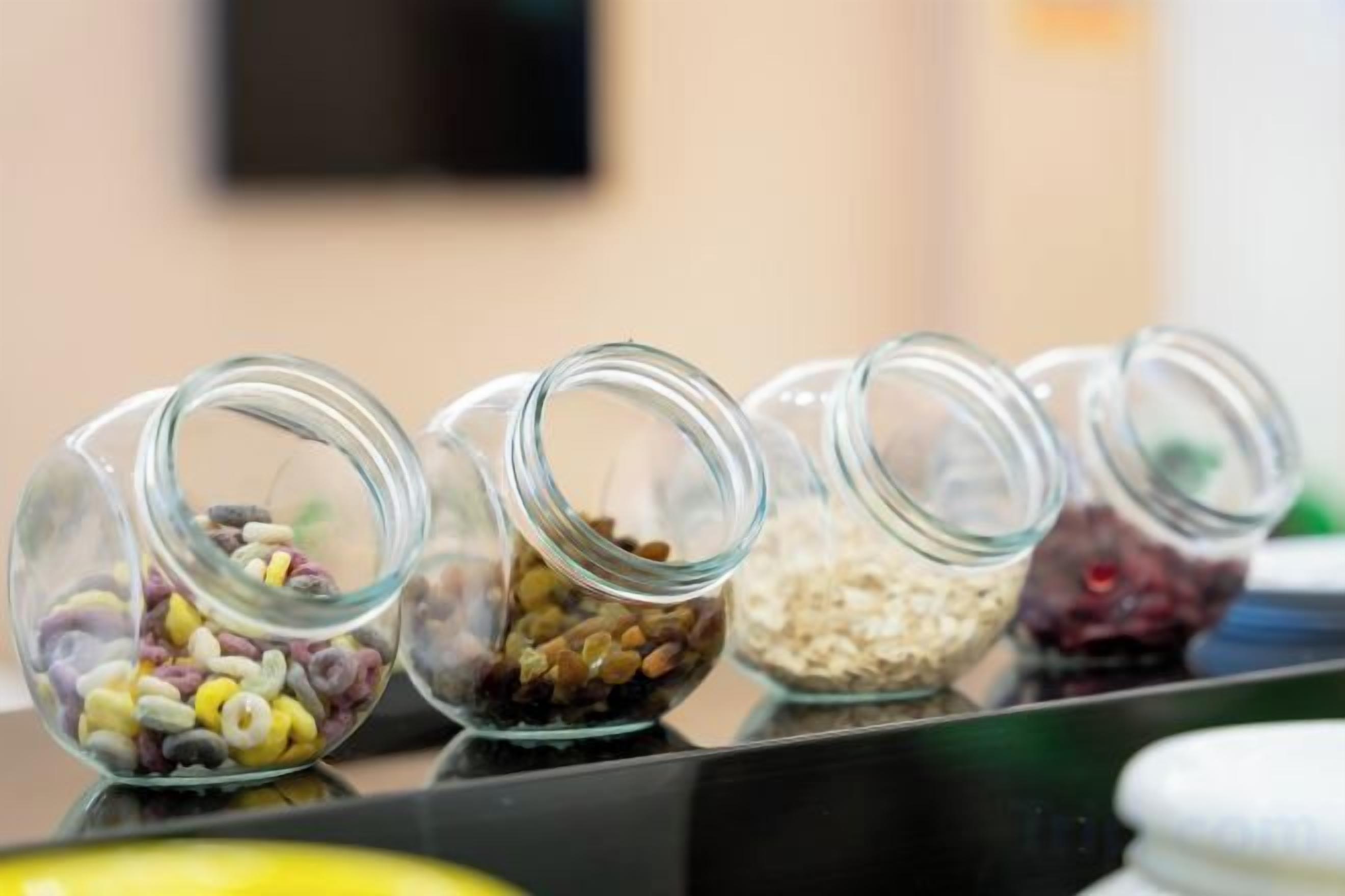 Una hilera de frascos de vidrio con diversos cereales y semillas.