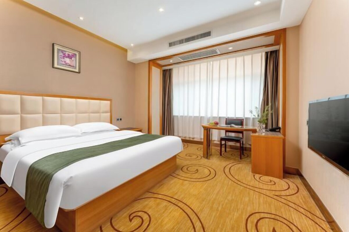 Habitación de hotel con una cama grande, un escritorio con computadora y televisión.