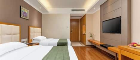A hotel room with two beds, a flat-screen TV, a desk, and a small table with fruit.