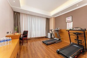 A hotel room with a wooden desk, two treadmills, a chair, and a large window with curtains. - GreenTree Inn (Feicheng Xincheng Road) (Feicheng)