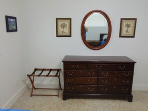 A room with a wooden dresser, a mirror, and two framed pictures on the wall.