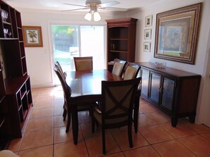 A dining area with a wooden table and chairs, a bookshelf, and a cabinet.