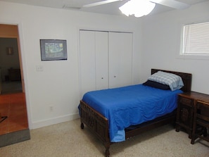 A bedroom with a bed, a wardrobe, a nightstand, and a framed picture on the wall.