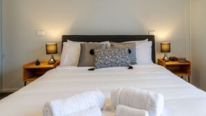 A neatly made bed with white linens, two bedside tables with lamps, and a pillow with a leaf pattern. - Bright and Spacious 2BR near Ara Institute and CBD (Christchurch)