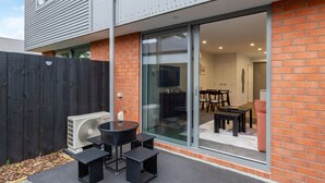 A modern house with a patio area featuring a glass door leading to an indoor dining space. - Bright and Spacious 2BR near Ara Institute and CBD (Christchurch)