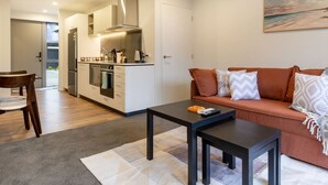 A modern apartment with a kitchen, a living area with a sofa and coffee table, and a dining area with a chair. - Bright and Spacious 2BR near Ara Institute and CBD (Christchurch)