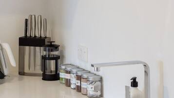 Una cocina moderna con un lavamanos de acero inoxidable, una cafetera y un bloque de cuchillos.