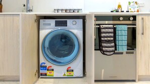 Una lavadora y secadora compactas con calificaciones de eficiencia energética y de agua, una cocina con microondas y un tendedero para toallas.