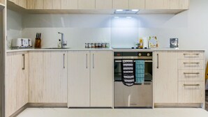 Una cocina moderna con armarios de madera clara, horno empotrado y campana extractora de acero inoxidable.