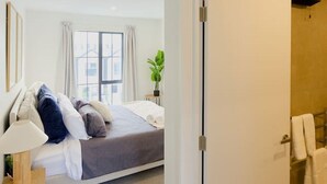 Une chambre à coucher moderne avec un lit, une table de chevet et une vue sur la salle de bain.