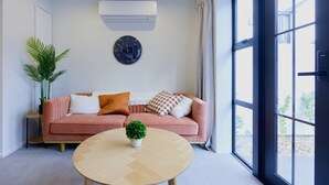 Un salon moderne avec un canapé rose, une table basse ronde en bois et une plante en pot.
