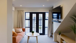 Un salon moderne avec un canapé, une table ronde et un téléviseur fixé au mur.
