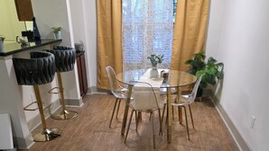 Un comedor con una mesa y sillas de vidrio, una cafetera y una planta.