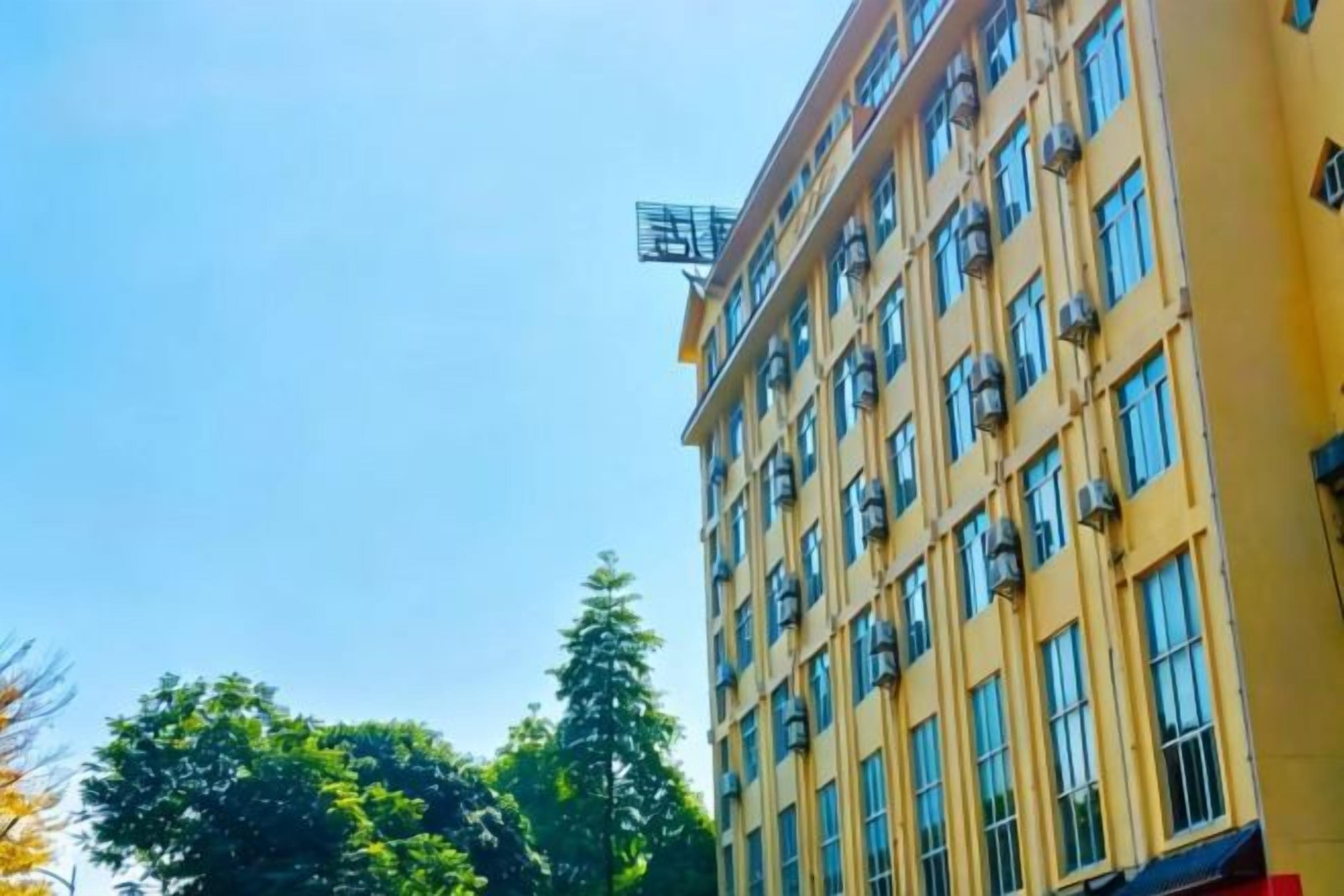 A multi-story building with a yellow facade and numerous windows.