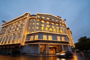 Un hotel de varios pisos con una entrada destacada y señalización iluminada.