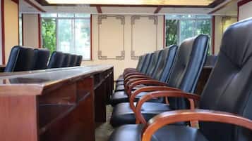 Un salón de conferencias con una larga mesa y filas de sillas.