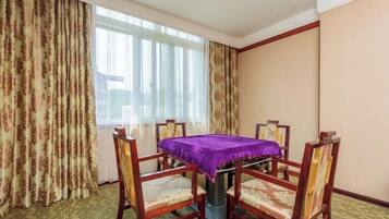 Una habitación de hotel con una mesa de comedor, cuatro sillas y un ventanal con cortinas.
