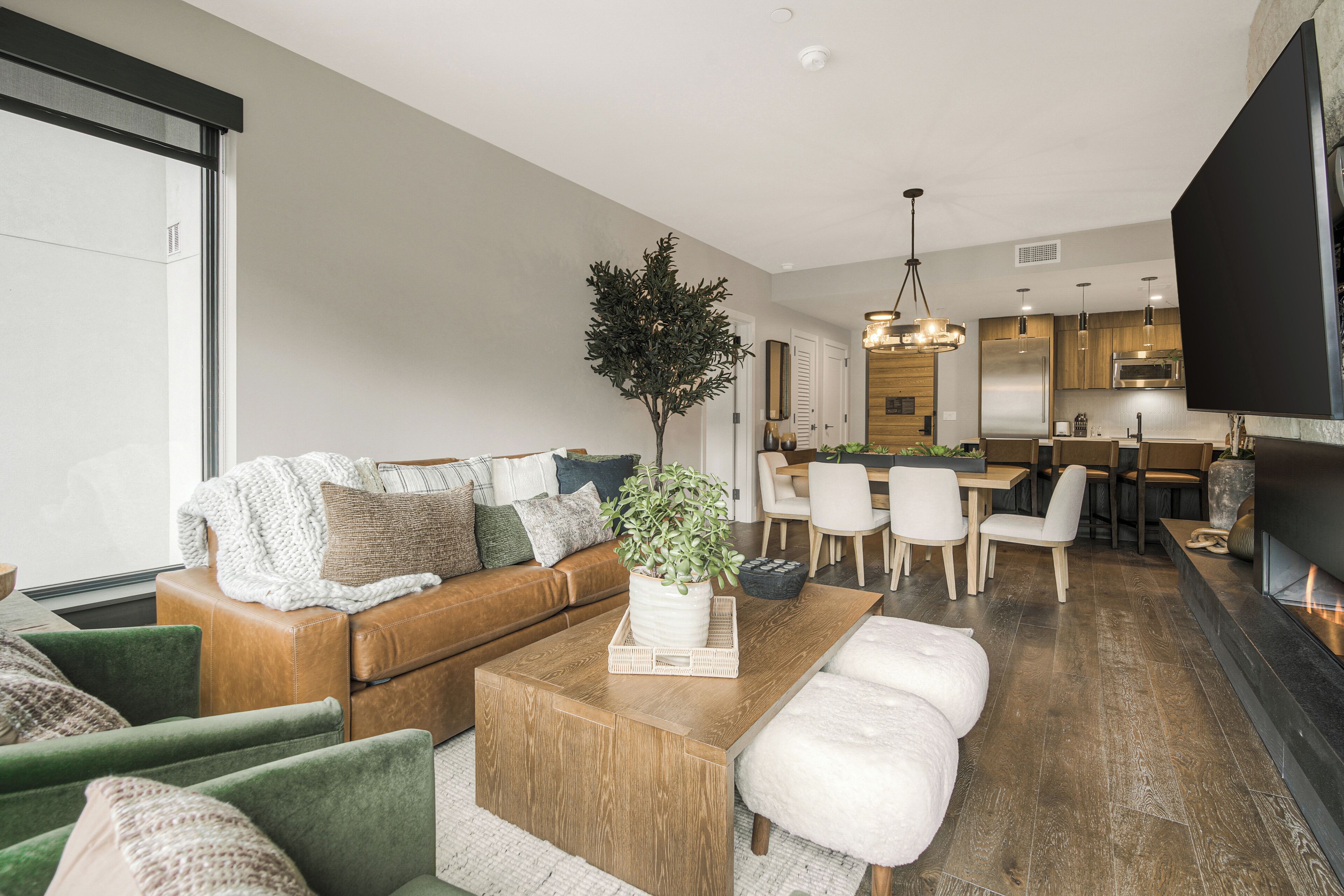 A modern living room with a sofa, coffee table, and a dining area with chairs and a table.