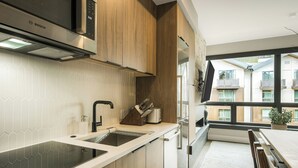 Una cocina moderna con un microondas Bosch, armarios de madera, un lavabo y una ventana con vista a un edificio.