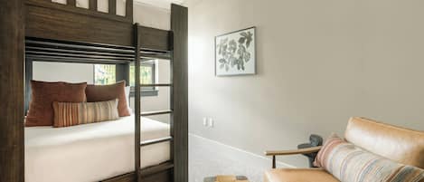 Un lit superposé avec des oreillers, un canapé, une petite table et un tableau encadré au mur.