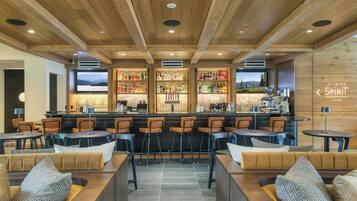 A bar area with wooden ceiling, bar stools, and a bar counter with bottles.