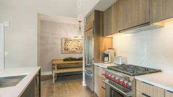 Una cocina moderna con armarios de madera, electrodomésticos de acero inoxidable, un banco empotrado y una lámpara colgante.