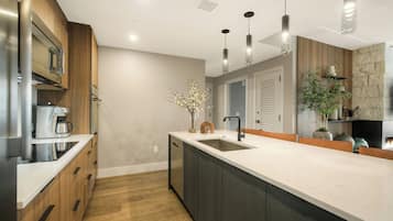 A modern kitchen with a large island, stainless steel appliances, and pendant lighting.