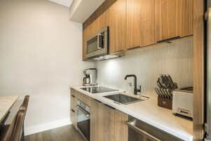 Cocina moderna con armarios de madera, electrodomésticos de acero inoxidable, un lavamanos doble y un tostador.