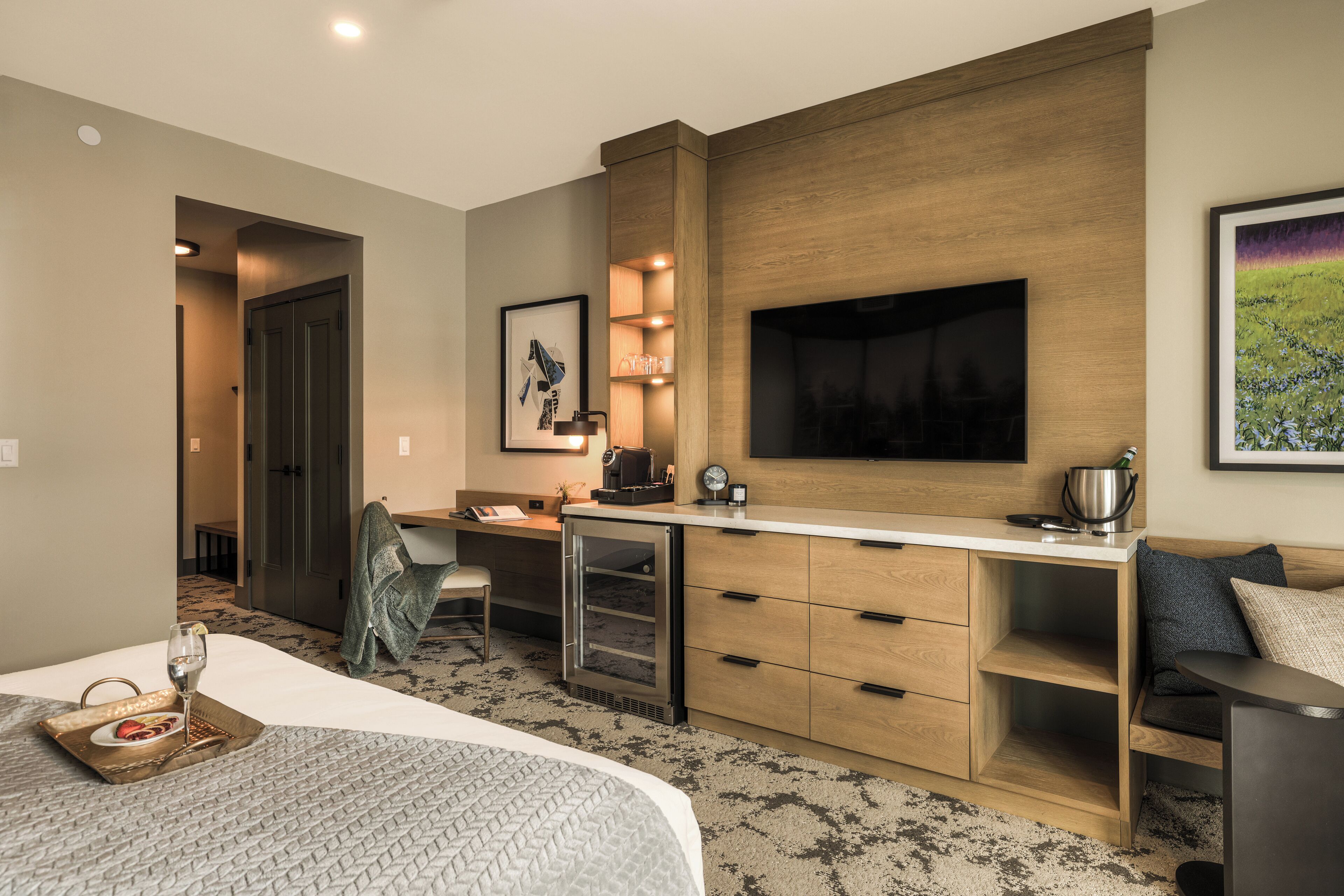 Habitación de hotel con cama, escritorio, televisión y kitchenette.