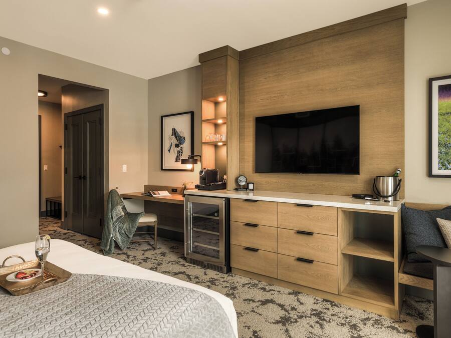 Habitación de hotel con cama, escritorio, televisión y kitchenette.