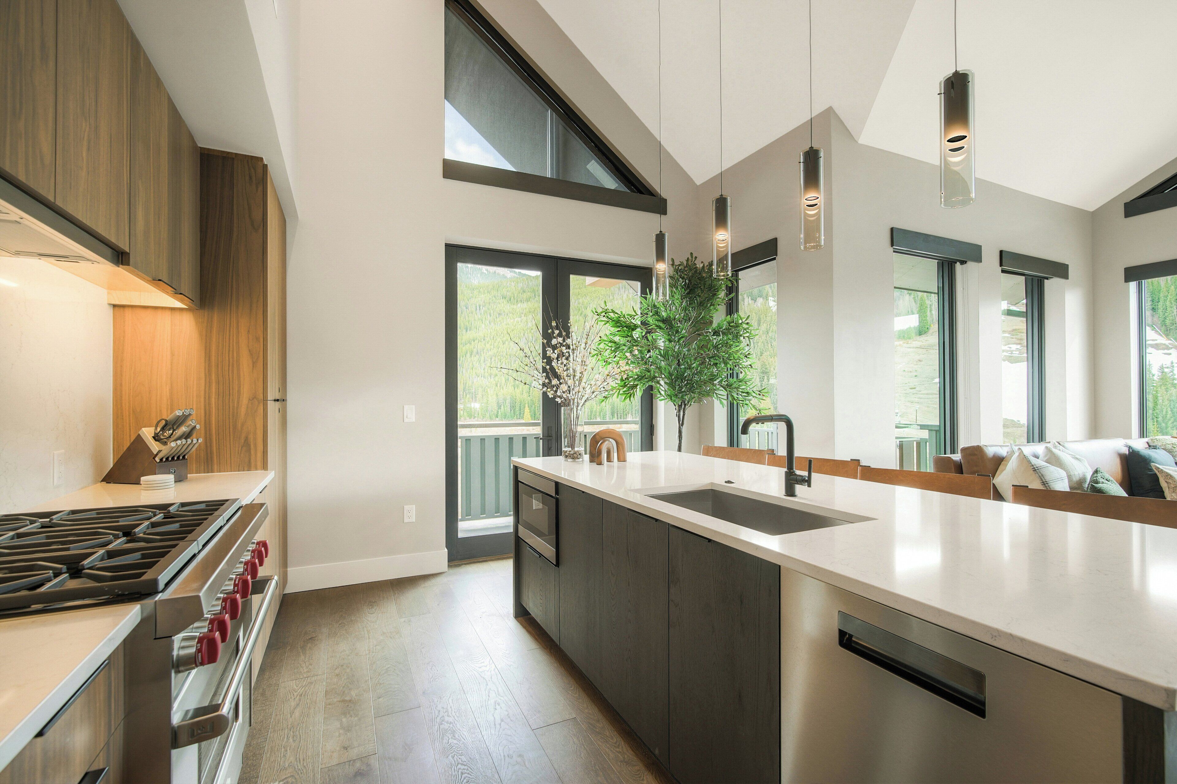 A modern kitchen with a large island, stainless steel appliances, and large windows.