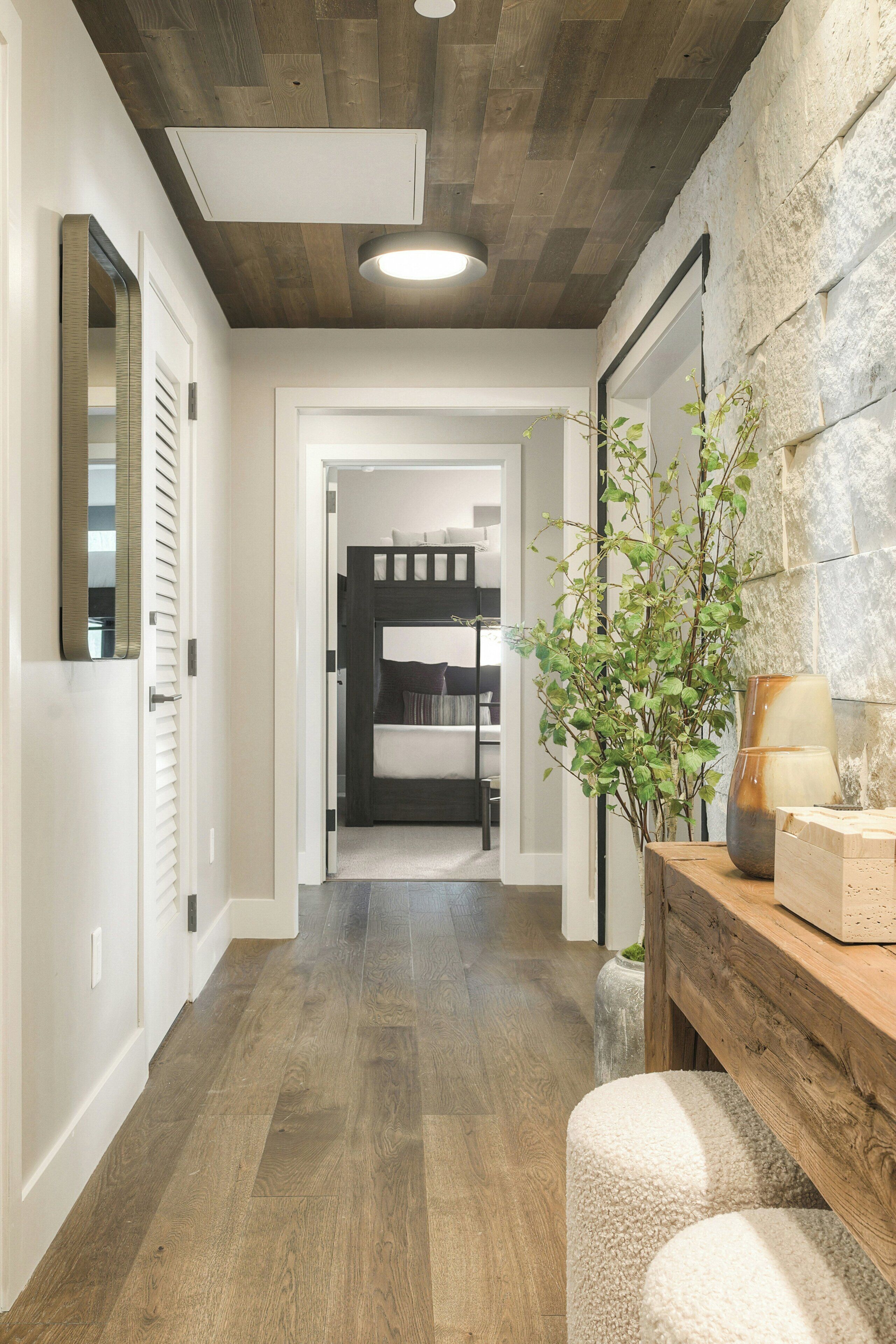 Un couloir avec un plancher en bois, un banc, une plante en pot et un mur en pierre.