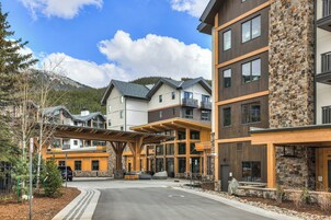 A multi-story hotel with a stone facade, balconies, and a covered entrance area.