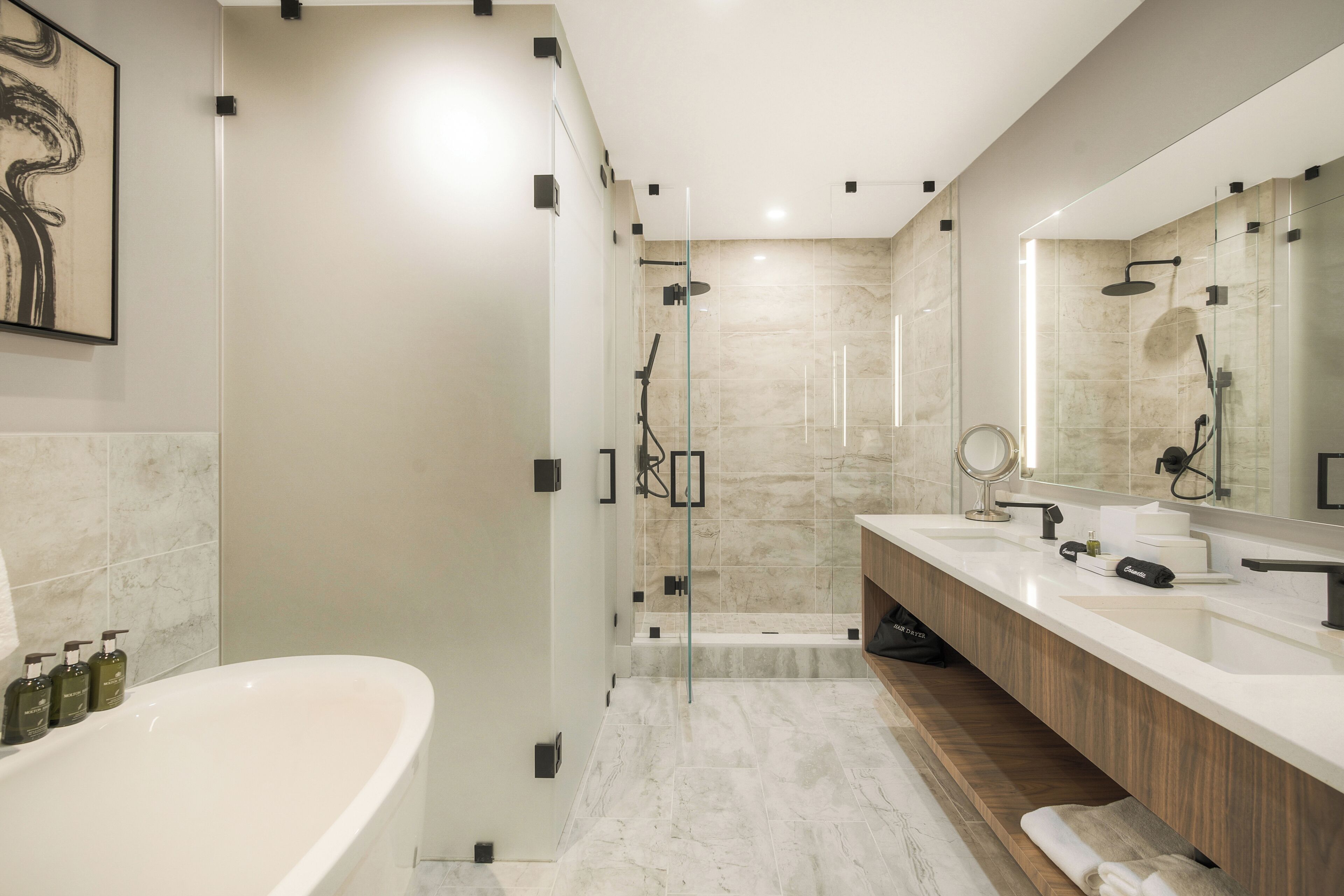 A modern bathroom with a freestanding bathtub, a glass-enclosed shower, and a vanity with a mirror.