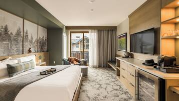 A hotel room with a large bed, a desk, a flat-screen TV, and a view of a building through the window.