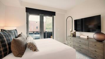 Un dormitorio con cama, cómoda, televisor y balcón con vistas.
